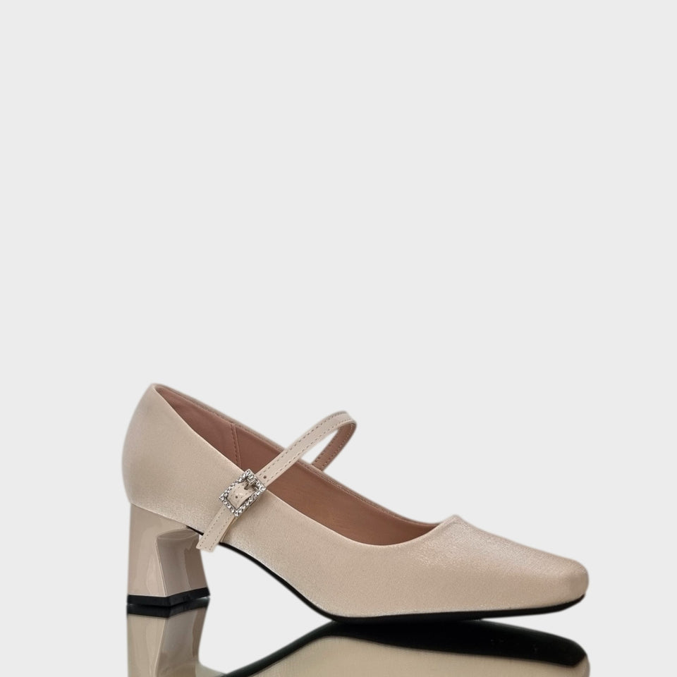 Vista en diagonal de los Zapatos Emma Champagne, de estilo francés, en materail satinado natural, con taco bloque de acrílico al tono de 5 cm, y correa de charol que se ajusta  al empeine con una delicada hebilla de strass