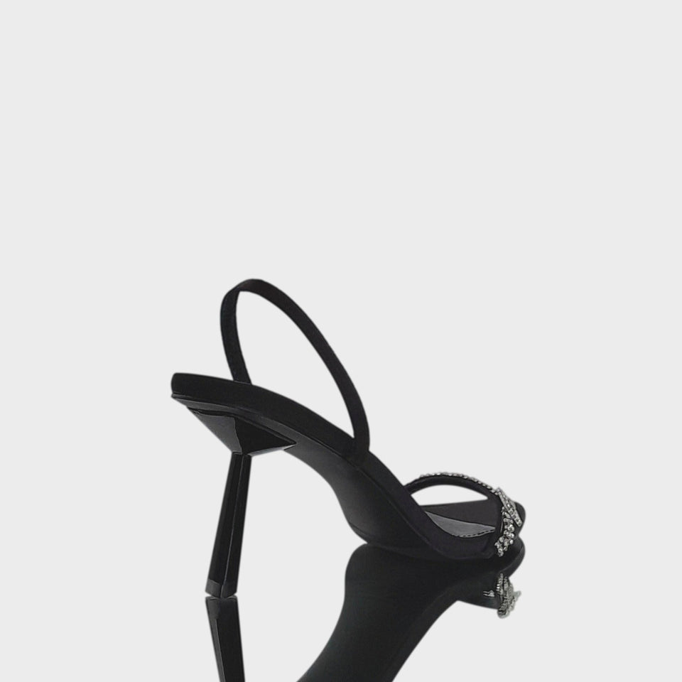 Vista de talón y taco de las sandalias Carol Black, en raso negro, con tira de strass sobre los dedos y taco geométrico de 8 cm en acrílico al tono