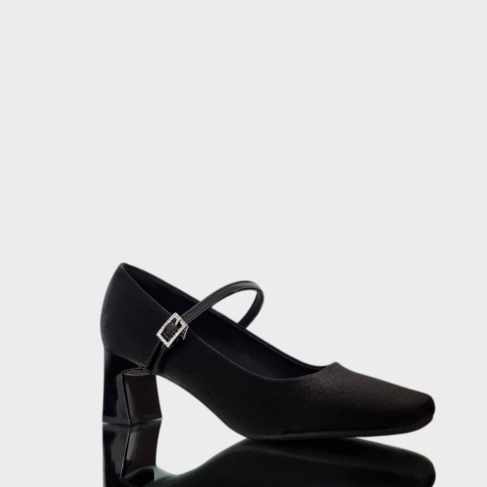Vista en diagonal de Zapatos Emma Black, de estilo francés, en materail satinado negro, con taco bloque de acrílico al tono de 5 cm, y correa de charol que se ajusta  al empeine con una delicada hebilla de strass