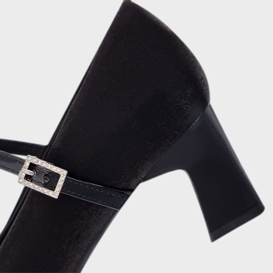 Vista en detalle del taco de los Zapatos Emma Black, de estilo francés, en materail satinado negro, con taco bloque de acrílico al tono de 5 cm, y correa de charol que se ajusta  al empeine con una delicada hebilla de strass