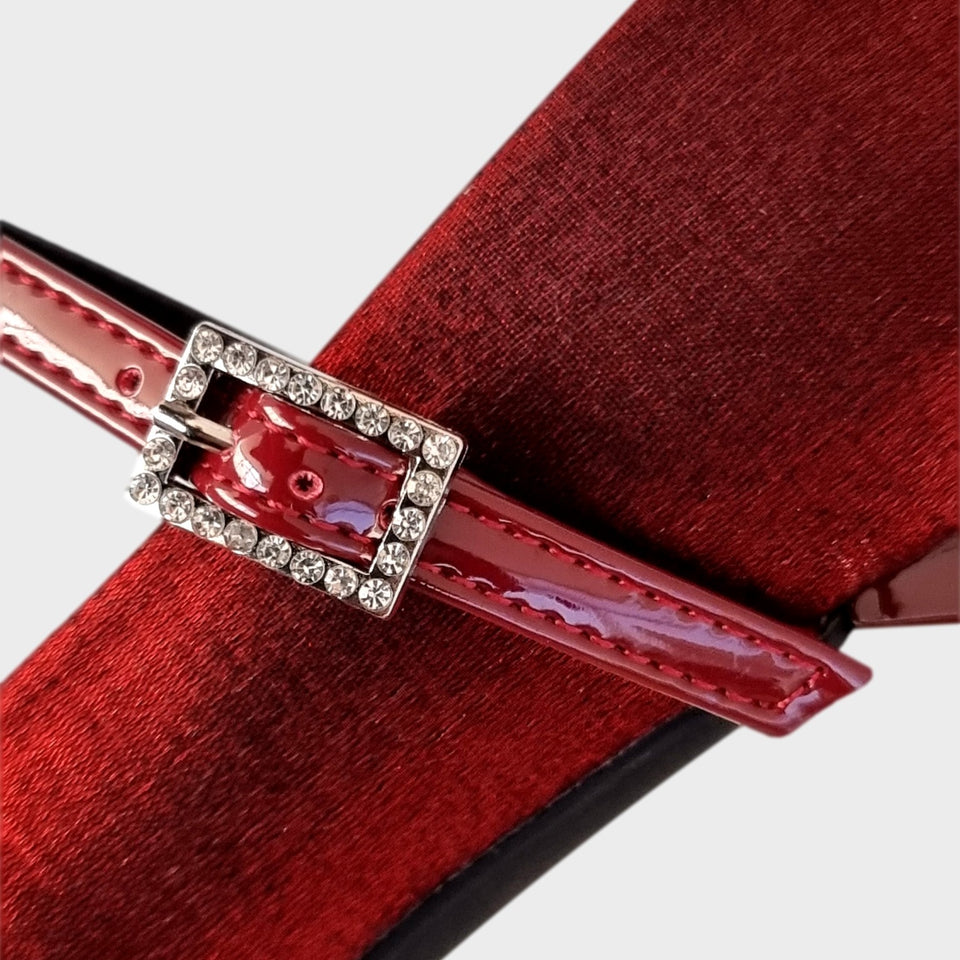 Vista en detalle de la hebilla de los Zapatos Emma Bordeaux, de estilo francés, en materail satinado bordeaux, con taco bloque de acrílico al tono de 5 cm, y correa de charol que se ajusta  al empeine con una delicada hebilla de strass