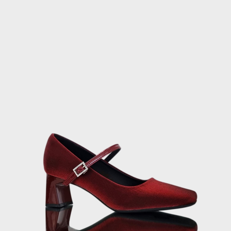 Vista en diagonal de los Zapatos Emma Bordeaux, de estilo francés, en materail satinado bordeaux, con taco bloque de acrílico al tono de 5 cm, y correa de charol que se ajusta  al empeine con una delicada hebilla de strass
